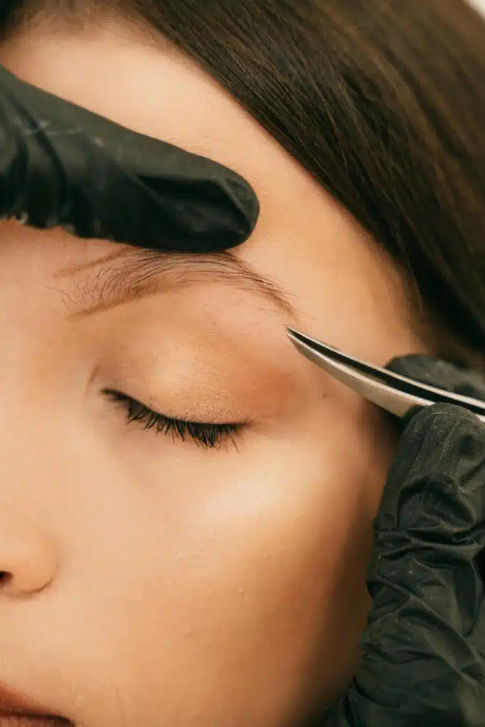 Femme en train de se faire épiler les sourcils à la pince avec précision.