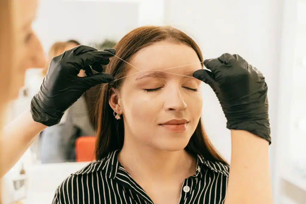 Femme en train de se faire épiler les sourcils avec la technique d'épilation au fil.