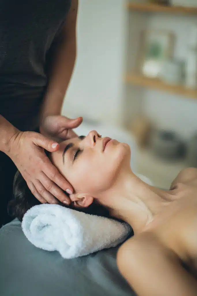 Femme en train de démarrer un soin du visage et de se faire masser les côtés du visage.