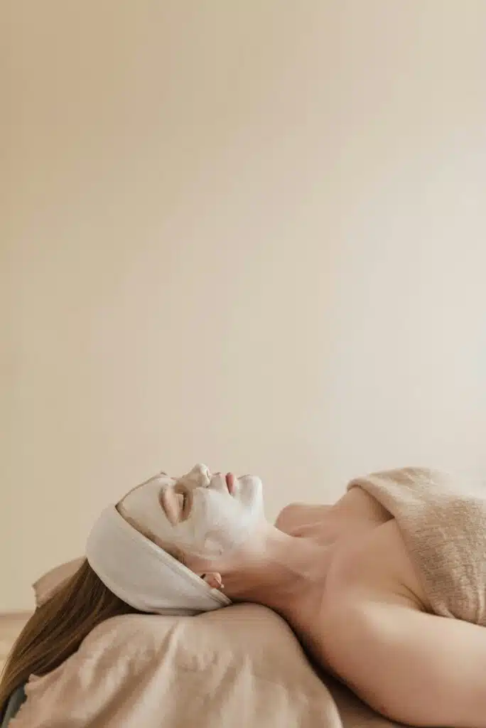 Femme allongés sur une table de massage avec un masque relaxant sur son visage.