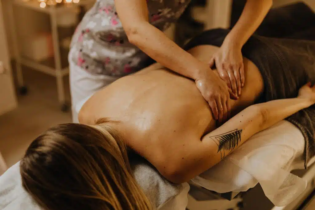 Femme allongée sur une table de massage en train de se faire masser le dos par une professionnelle.