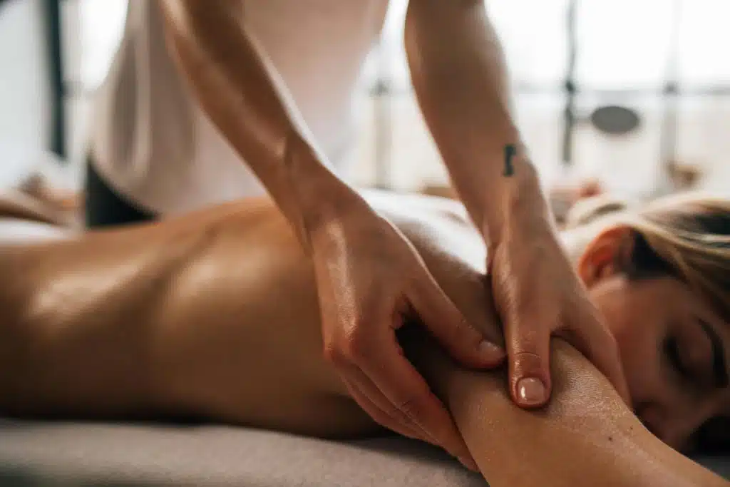 Femme allongée sur une table de massage en train de se faire masser le dos par une professionnelle.
