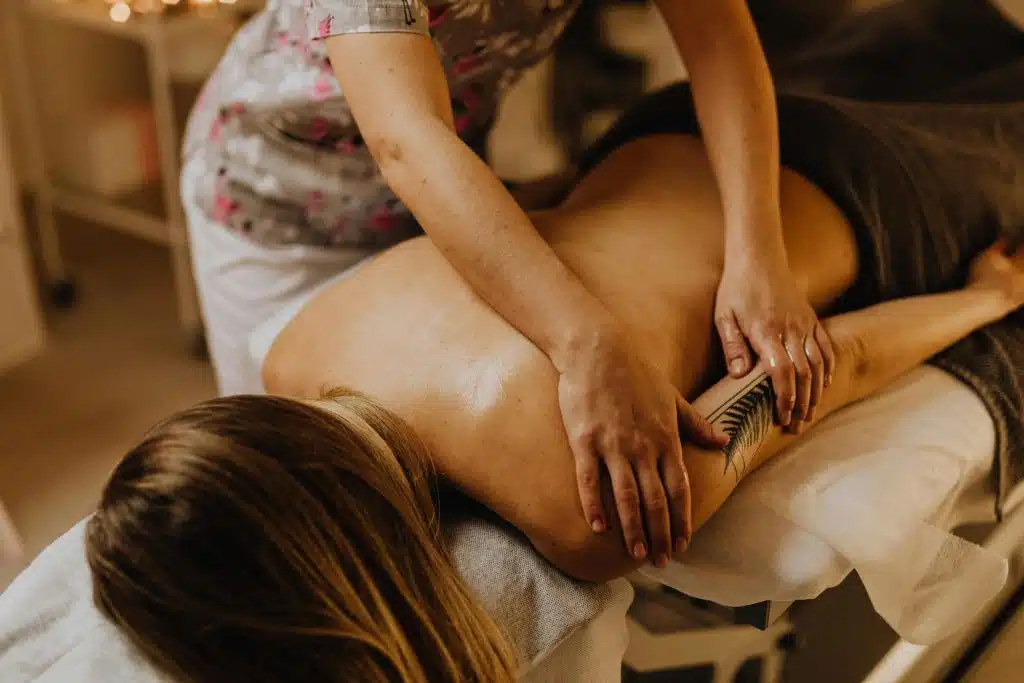 Femme allongée sur une table de massage en train de se faire masser le dos par une professionnelle.