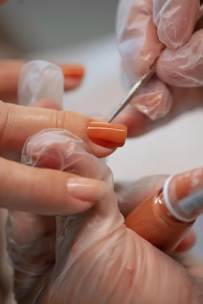 Professionnelle en train de déposer un semi permanent sur les mains d'une cliente.