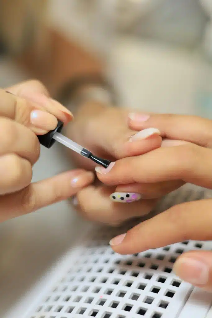 Professionnelle en train de déposer un semi permanent sur les mains d'une cliente.