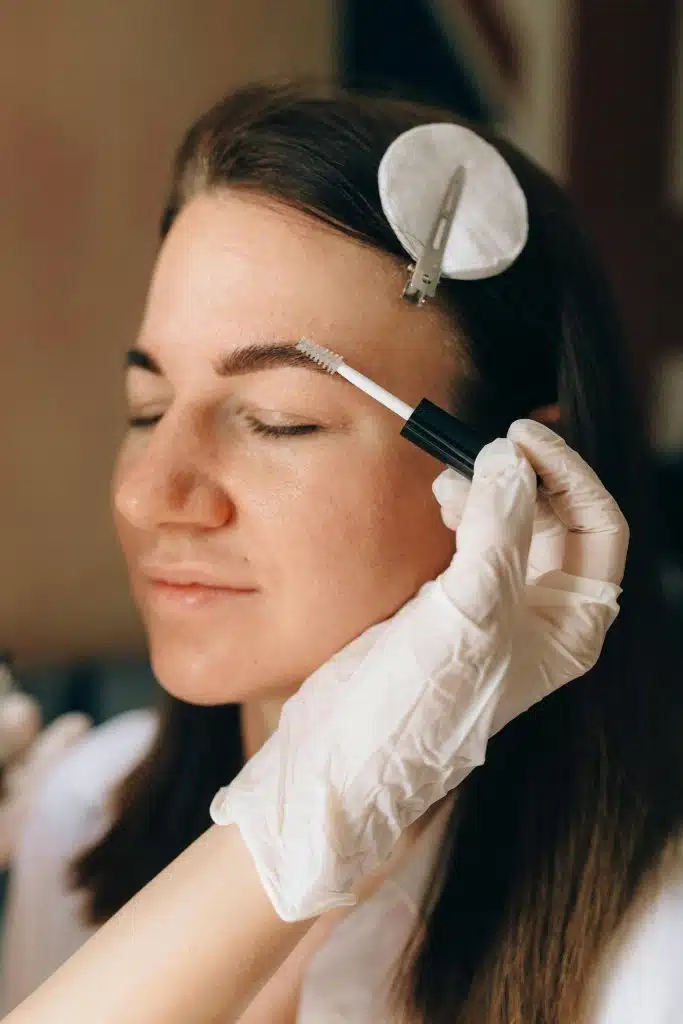 Femme en pleine teinture des sourcils par une professionnelle.